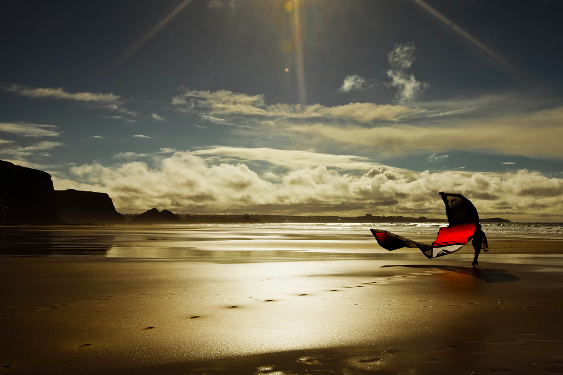 Nice start to an end of the day soul surfing session - kitesurfer walking on the beach with kite