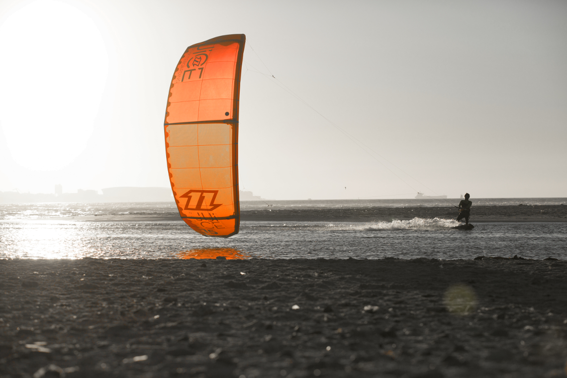 A kitesurfer cruising on the 2015 North kiteboarding Juice kite around sunset in light winds.