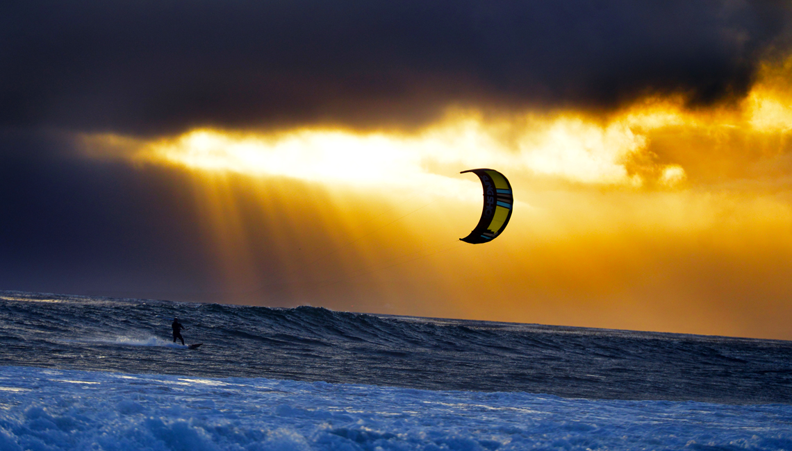 A kitesurfer cruising at sunset with his 2016 Slingshot Wave SST kite.