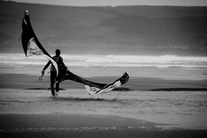 Kitesurfer walking on the beach with his kite.