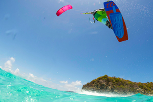 The 2016 North Kiteboarding Rebel kite and Gambler board over tropical waters. Kiteboarder jumping while girl dives under water.