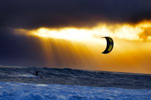 A kitesurfer cruising at sunset with his 2016 Slingshot Wave SST kite.